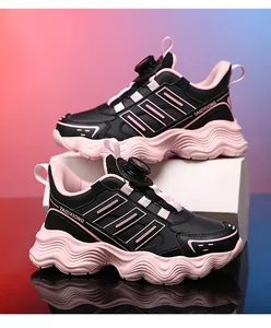 Side detail of kids' athletic shoes featuring a rotary buckle and pink wavy soles.