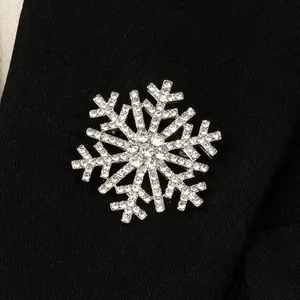Macro view of a sparkling snowflake brooch with clear rhinestones on black fabric.