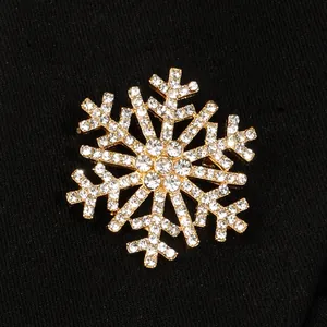 Detailed close-up of a festive gold-toned snowflake brooch with sparkling clear rhinestones.