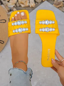 Vue détaillée de sandales plates jaunes avec boucles en strass élégantes et bout ouvert.