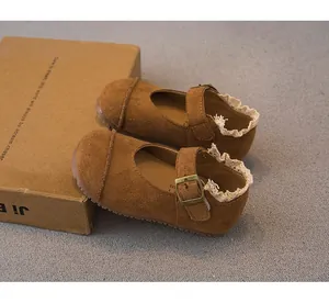 Close-up detail of brown suede girls' Mary Jane shoes with lace trim and buckle strap