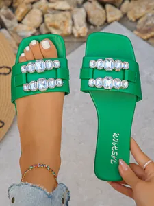 Vue détaillée de sandales plates vertes ornées de grands strass brillants sur les brides