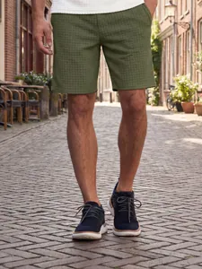 Detail view of olive green waffle texture shorts for men in a casual street setting