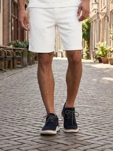 Close-up detail of white waffle knit men's leisure shorts on a cobblestone street