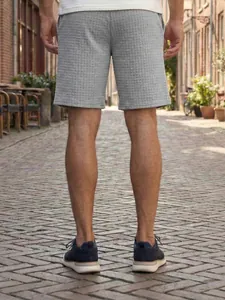 Detailed back view of grey men's casual shorts with small grid texture in street setting