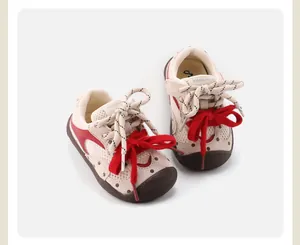 Detailed macro view of cream toddler pre-walker sneakers featuring stylish red bow accents