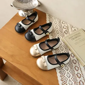 Chaussures Mary Jane élégantes pour filles en noir et or sur une table en dentelle vintage.