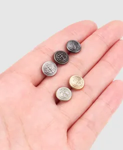Close-up of premium brass anchor design buttons displayed on a human palm for scale
