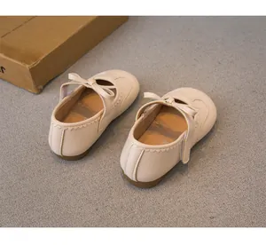 Chaussures Mary Jane en cuir beige pour fille avec nœud délicat et bord festonné.