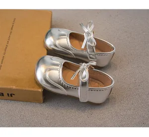 Détail de chaussures Mary Jane argentées pour filles avec nœud et bords festonnés