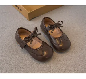 Détail des chaussures Mary Jane marron foncé pour filles avec nœud et coutures ondulées