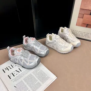 Gros plan sur des baskets pour enfants argentées et crème avec laçage à cadran