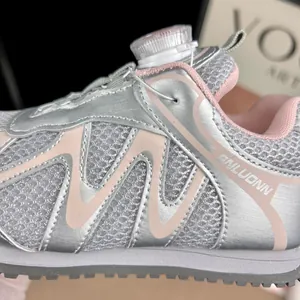 Gros plan sur des baskets argentées respirantes pour enfants avec maille et laçage à bouton
