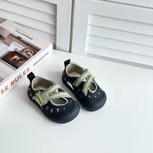 Nahaufnahme von atmungsaktiven schwarz-grünen Mesh-Kindersandalen auf weißem Tisch