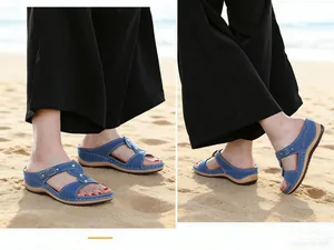 Comfortable blue women's wedge sandals with metal buckles shown on a sunny sandy beach