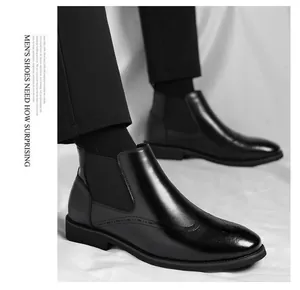 Dettaglio stivali Chelsea da uomo in pelle nera con eleganti decorazioni brogue.