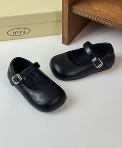 Close-up view of retro black Mary Jane leather shoes for toddler girls in a minimal setting.