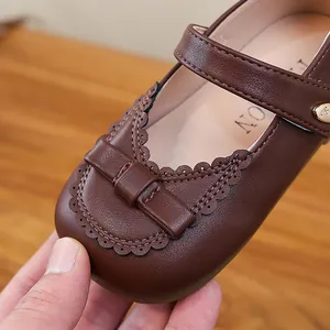 Elegant brown Mary Jane shoes for girls featuring a cute bow and scalloped trim details