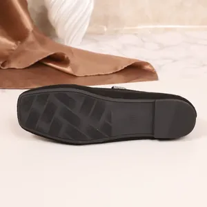 Gedetailleerd macrozicht op de rubberen antislipzool van zwarte suède loafers met strass
