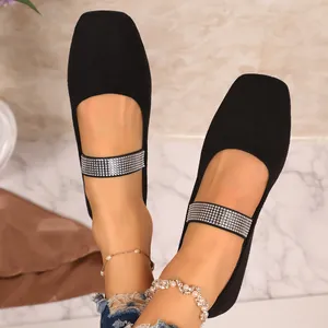 Close-up van zwarte suède platte schoenen met sprankelende decoratieve bandjes van strass