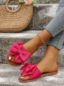 Primer plano de sandalias fucsia con lazo usadas en escalones de hormigón
