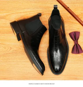 Overhead view of black leather Chelsea boots with intricate engraved patterns and bowtie