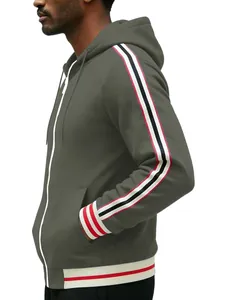 Detail view of the red and white striped webbing on the sleeve of a green hoodie