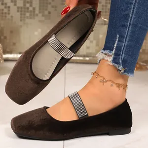 Detailopname van bruine suède platte schoenen met glanzende strasstenen bandjes