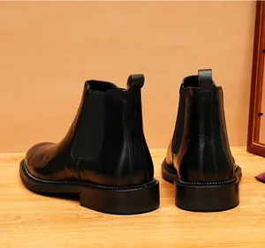 Macro view of men's black leather Chelsea boots featuring unique script embossing