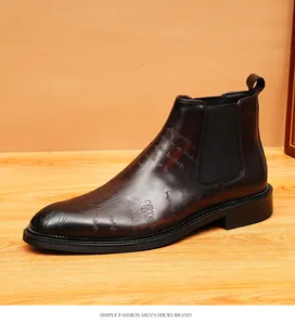 Close-up of vintage brown leather Chelsea boots with unique script pattern engraving.