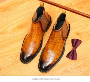 Detailed macro view of brown leather Chelsea boots with retro etched script patterns.