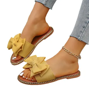 Elegantes sandalias planas amarillas con un gran lazo de tela y suela decorada para mujer
