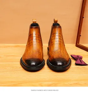 Macro view of tan leather Chelsea boots showing engraved script and burnished finish