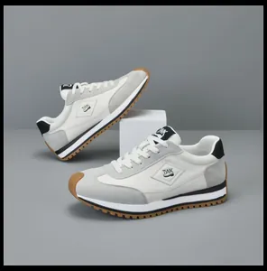 Stijlvolle heren sneakers van grijs en wit leer met gomzool op een studio achtergrond.