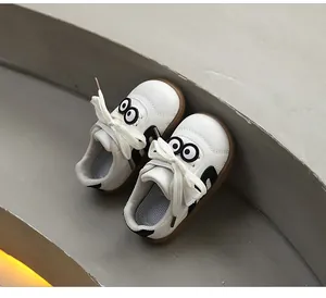 Detailed view of white toddler sneakers featuring cute cartoon eye motifs on concrete stairs