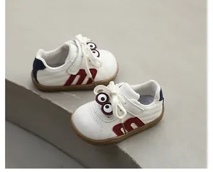 Detailed view of white toddler sneakers with red M-letter and cartoon eye decor