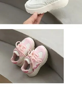 Détail de baskets compensées pour enfants rose et blanc sur un escalier gris