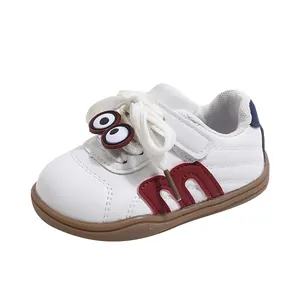Detailed view of white baby toddler shoes with cartoon eyes and red M design