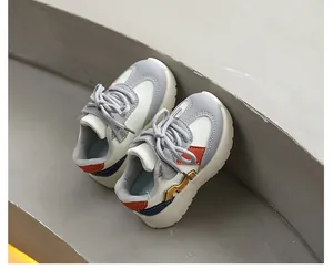 Détail de baskets sportives pour enfants aux couleurs vives sur une marche grise épurée