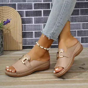 Nahaufnahme beiger Peep-Toe-Keilsandaletten mit Goldschnalle auf rustikalem Holzboden