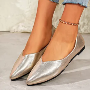 Detailed close-up of elegant champagne metallic pointed-toe ballet flats worn with an anklet