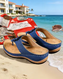 Tongs compensées bleues à détails floraux découpés au laser sur une plage de sable