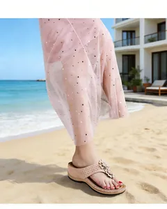 Vue rapprochée de sandales compensées pour femmes avec décor floral sur une plage