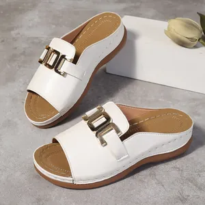 Detailansicht weißer Damen-Keilsandalen mit goldener Schnalle und brauner Sohle.