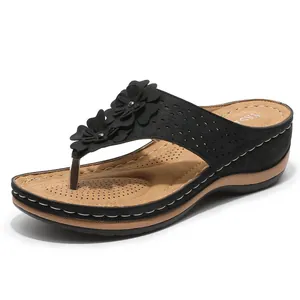 Tongs compensées noires confortables pour femmes avec fleurs et motifs découpés au laser.