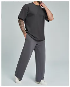 Vista de cuerpo completo de un hombre con camiseta gris oscuro holgada y pantalón ancho casual