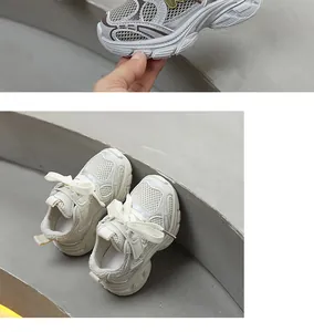 Vue détaillée de baskets respirantes blanc crème pour enfants sur une marche
