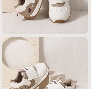 Close-up detail of cream baby walking shoes with cartoon heart design and Velcro strap.