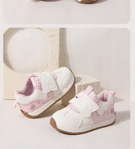 Close-up of pink and white baby sneakers with cute cartoon pattern and velcro strap