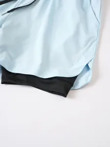 Detalle de pantalones cortos deportivos de doble capa para hombre en azul claro y negro